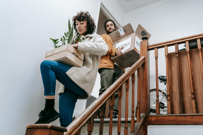 a couple carrying boxes down the stairs of their new home secured with a home equity loan from essential credit union