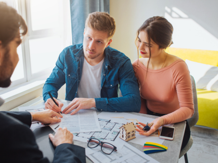 an employee of essential credit union gonzales helping a young couple sign for their home loan in gonzales