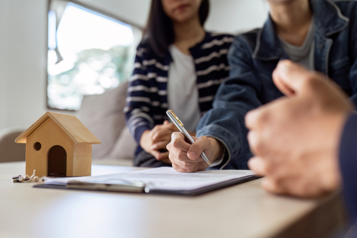 employee at essential credit union helping a young couple apply for a home loan for their first house